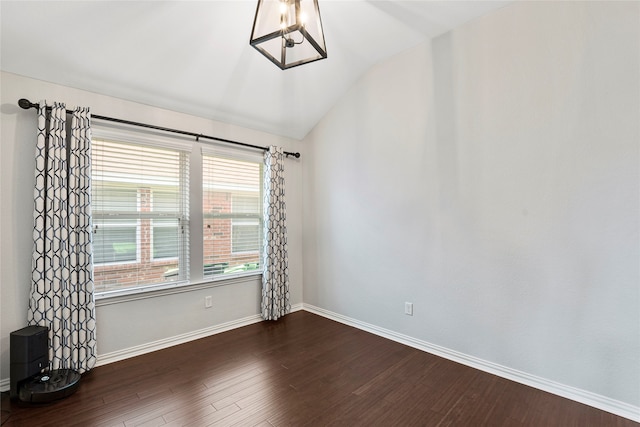 empty room featuring an inviting chandelier, dark hardwood / wood-style floors, and vaulted ceiling