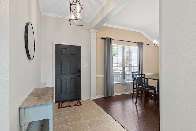 foyer featuring hardwood / wood-style floors, ornamental molding, an inviting chandelier, decorative columns, and lofted ceiling