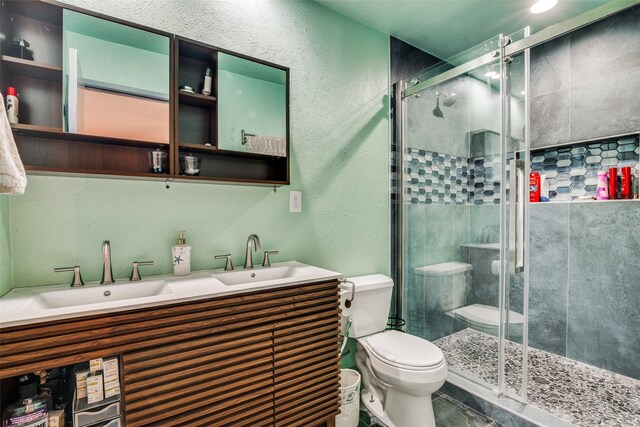 bathroom featuring tile patterned floors, a shower with door, toilet, and vanity