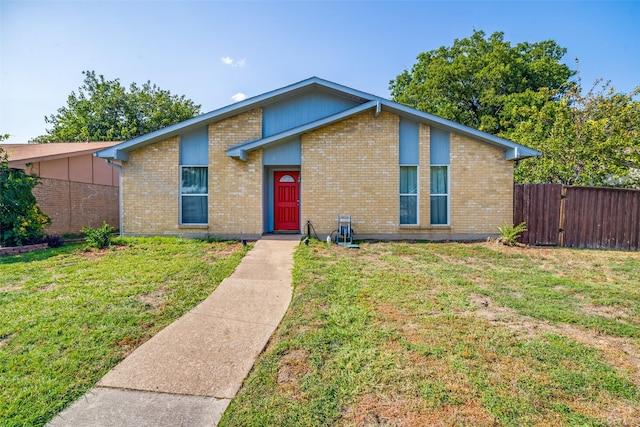 mid-century home featuring brick siding, fence, and a front lawn