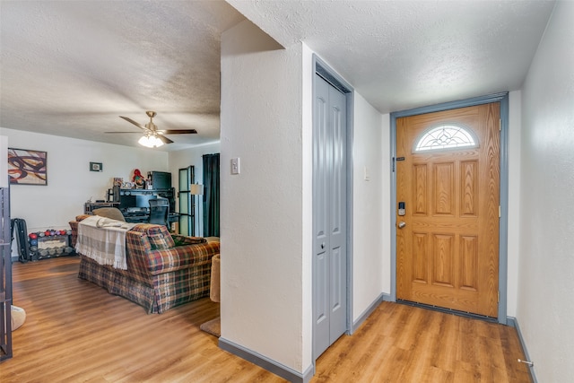 entrance foyer with light wood-type flooring, ceiling fan, and a textured ceiling