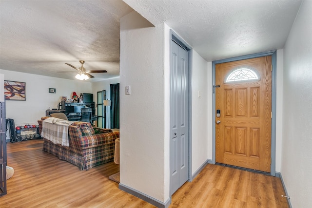 foyer with light wood-style flooring, baseboards, and a textured ceiling