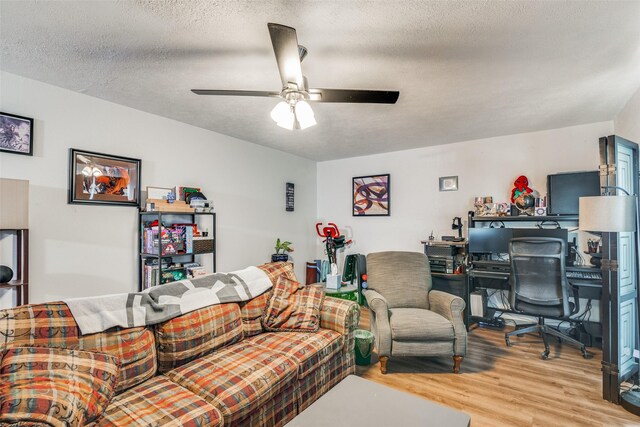 living room featuring light wood-type flooring, ceiling fan, and a textured ceiling