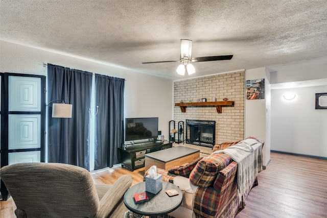 living room with wood-type flooring, a brick fireplace, and a textured ceiling