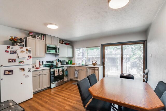 kitchen featuring a textured ceiling, appliances with stainless steel finishes, wood-type flooring, sink, and gray cabinetry