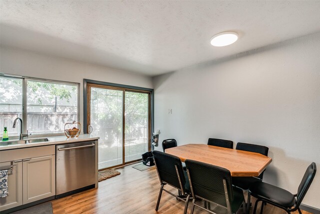 dining space with sink, light wood-type flooring, and a textured ceiling