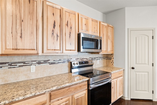 kitchen with stainless steel appliances, light stone countertops, backsplash, and light brown cabinetry