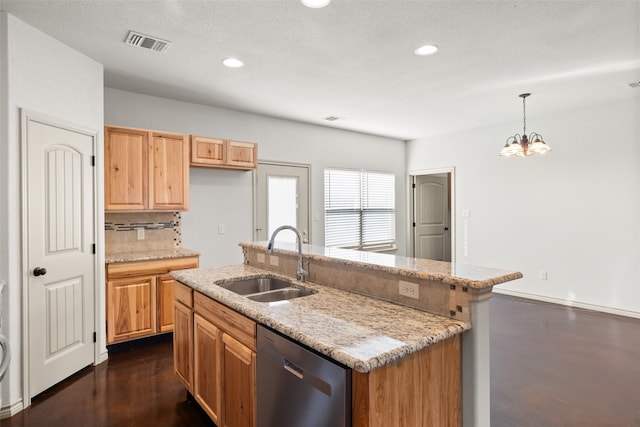 kitchen featuring dishwasher, decorative light fixtures, light stone countertops, sink, and an island with sink