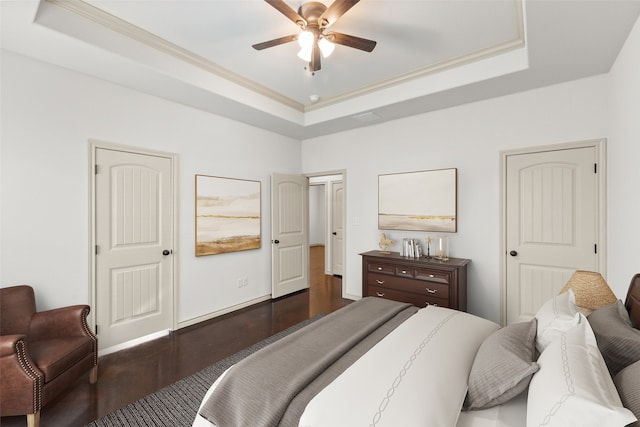 bedroom with dark hardwood / wood-style flooring, ceiling fan, and a raised ceiling