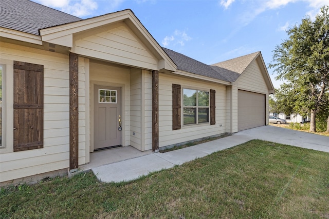 view of exterior entry featuring a lawn and a garage