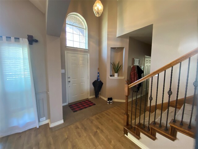 foyer featuring an inviting chandelier, wood-type flooring, and a high ceiling