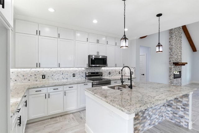 kitchen with sink, white cabinets, stainless steel appliances, and a kitchen island with sink