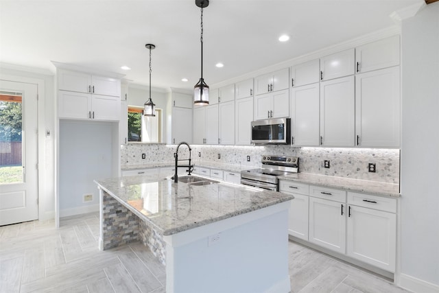 kitchen with sink, crown molding, an island with sink, stainless steel appliances, and white cabinets