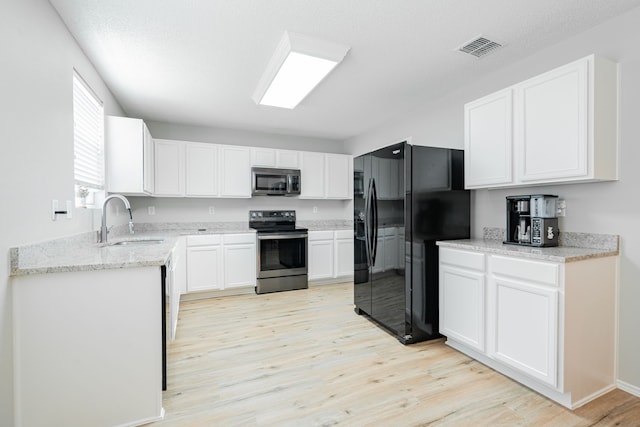 kitchen with stainless steel appliances, white cabinets, sink, light stone countertops, and light hardwood / wood-style flooring