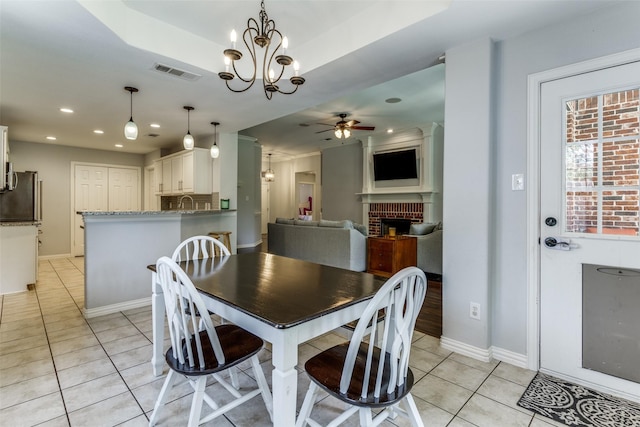 dining room with ceiling fan with notable chandelier, a fireplace, and light tile patterned flooring