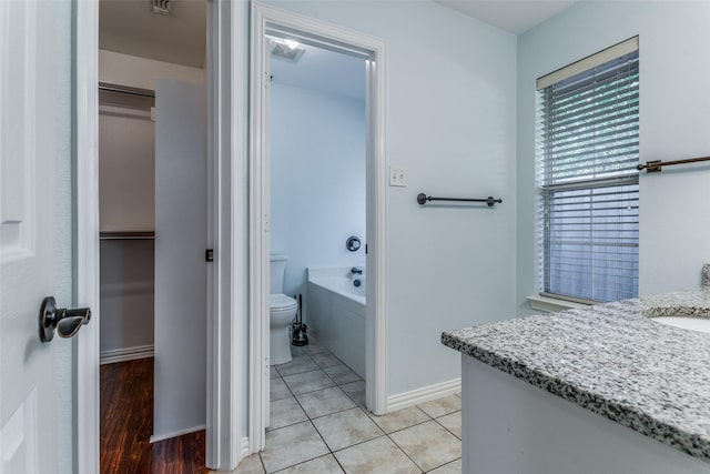 bathroom with vanity, toilet, tiled bath, and tile patterned flooring