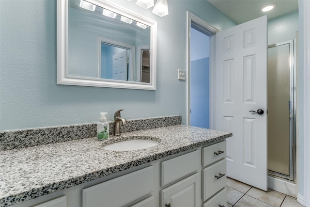 bathroom featuring a shower with door, vanity, and tile patterned flooring