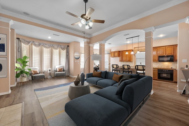 living room featuring hardwood / wood-style floors, decorative columns, ceiling fan, and ornamental molding