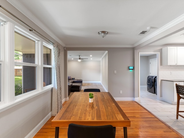 dining area with ornamental molding, washer and clothes dryer, and light wood-type flooring