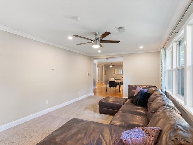 carpeted living room with ornamental molding and ceiling fan