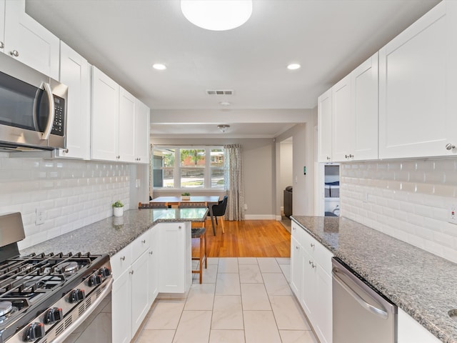 kitchen featuring backsplash, stone countertops, light wood-type flooring, and stainless steel appliances