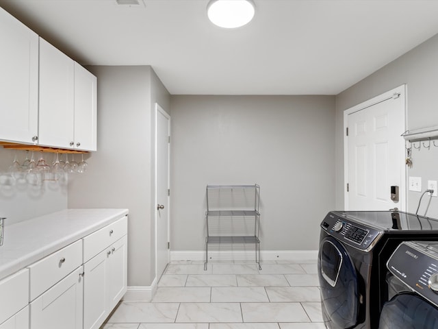 clothes washing area with cabinets, washing machine and dryer, and light tile patterned floors