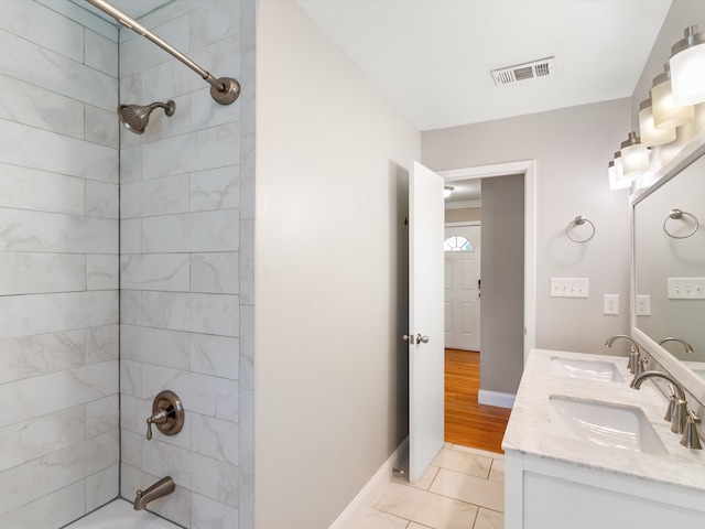 bathroom featuring double vanity, tiled shower / bath, and hardwood / wood-style floors