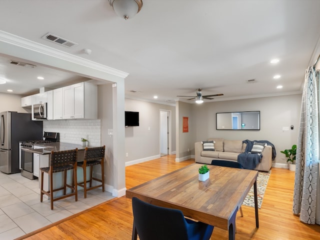 dining area featuring light hardwood / wood-style floors, crown molding, and ceiling fan