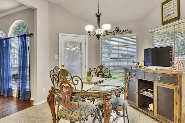 dining space with light tile patterned floors, ornamental molding, lofted ceiling, and an inviting chandelier