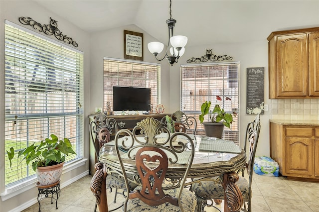 tiled dining space featuring lofted ceiling and a chandelier