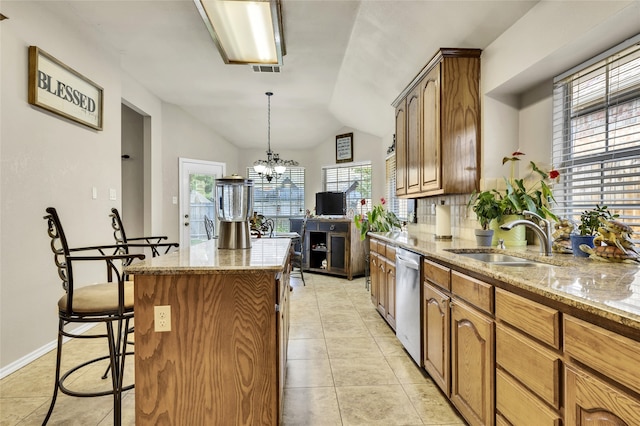 kitchen featuring a center island, lofted ceiling, sink, hanging light fixtures, and stainless steel dishwasher