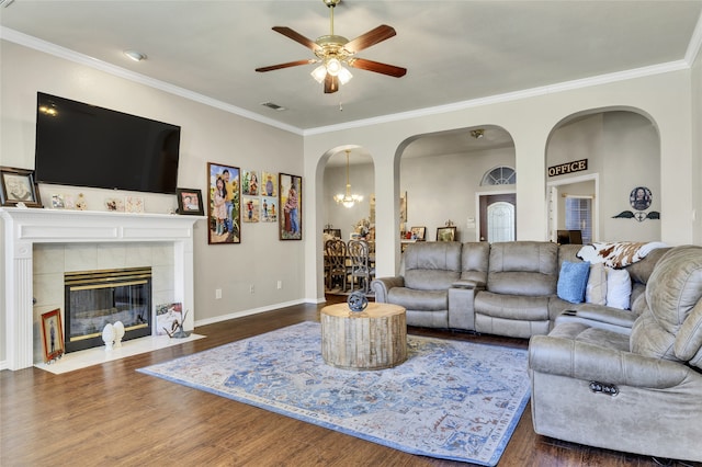 living room with a tiled fireplace, ornamental molding, and dark hardwood / wood-style floors