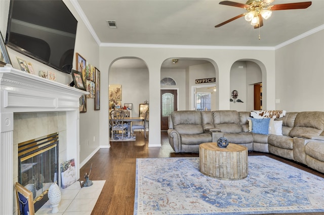 living room with ceiling fan, ornamental molding, a fireplace, and hardwood / wood-style floors