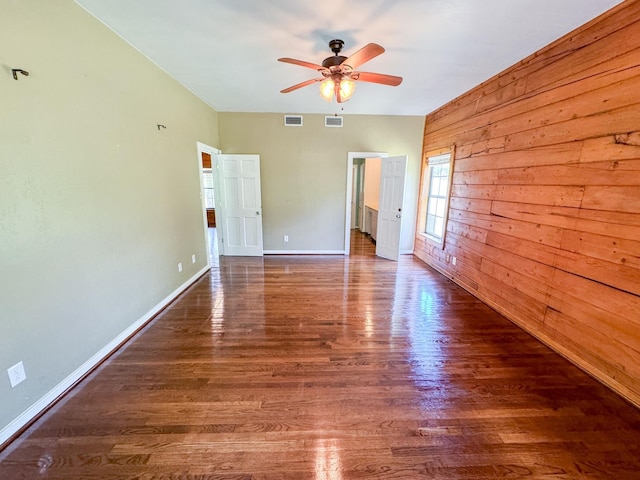 unfurnished bedroom with wood walls, hardwood / wood-style floors, and ceiling fan