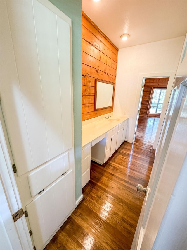 hallway featuring sink, wood walls, and dark hardwood / wood-style floors