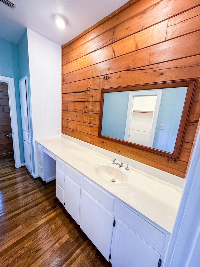 bathroom with hardwood / wood-style flooring, wooden walls, and vanity