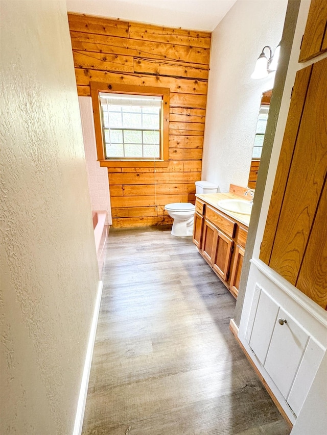 bathroom with wood walls, vanity, wood-type flooring, and toilet