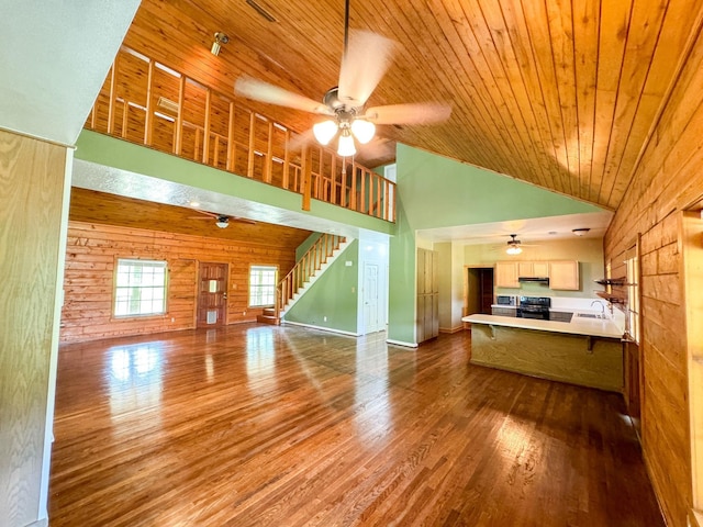 unfurnished living room with wood walls, wooden ceiling, ceiling fan, and wood-type flooring