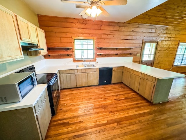 kitchen with light brown cabinetry, light hardwood / wood-style flooring, wooden walls, and black appliances