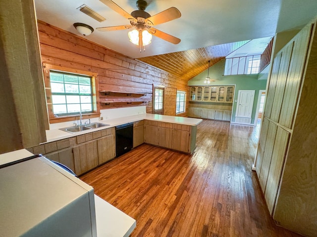 kitchen with wood walls, dark hardwood / wood-style floors, kitchen peninsula, and dishwasher