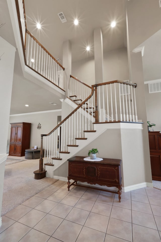 staircase featuring light tile patterned floors and a towering ceiling