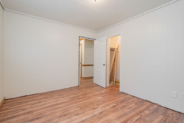 unfurnished bedroom with a textured ceiling, light wood-type flooring, a closet, and a spacious closet