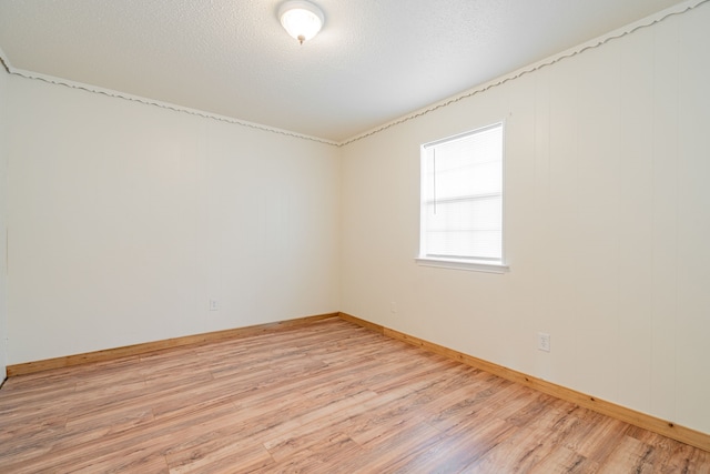 empty room with light hardwood / wood-style flooring and a textured ceiling