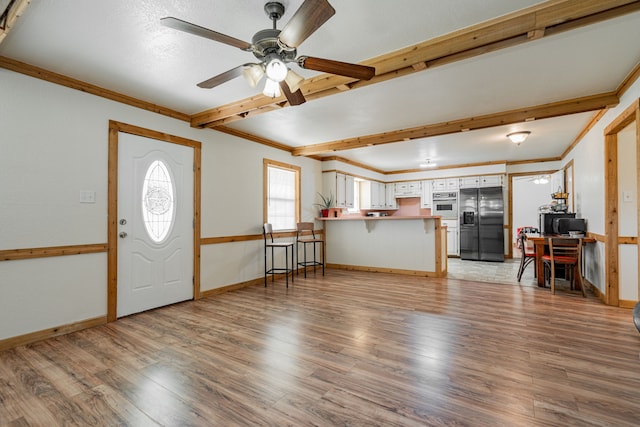 entryway with wood-type flooring, beam ceiling, ceiling fan, and crown molding