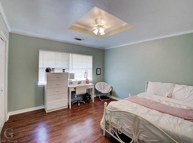 bedroom with dark wood-type flooring, ceiling fan, ornamental molding, and a raised ceiling