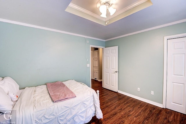 bedroom featuring a tray ceiling, dark wood-type flooring, and ornamental molding