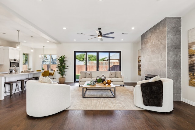 living room featuring dark hardwood / wood-style flooring, a tiled fireplace, and ceiling fan