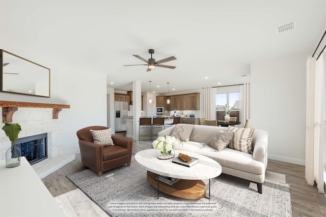 living room featuring a fireplace, light hardwood / wood-style flooring, and ceiling fan