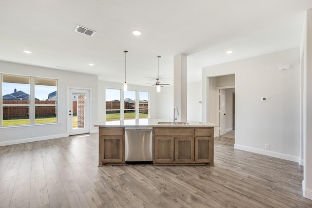 kitchen featuring sink, a healthy amount of sunlight, stainless steel dishwasher, decorative light fixtures, and a center island with sink