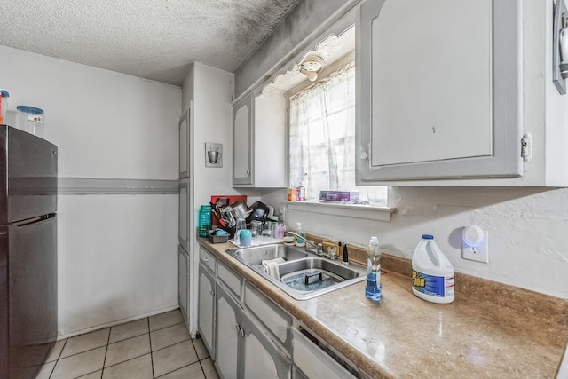 kitchen featuring light tile patterned flooring, stainless steel fridge, sink, and a textured ceiling